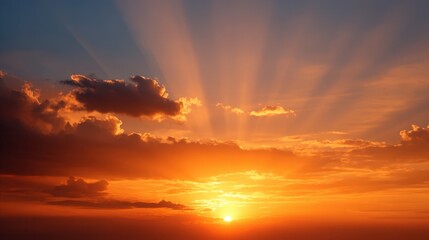 A breathtaking sunset featuring vibrant orange hues and rays of light piercing through scattered clouds.