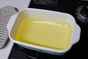 琺瑯鍋に油を注ぎ入れた調理準備の様子。天ぷらやカツなど揚げ物を作る前のリアルな家庭のキッチン風景。