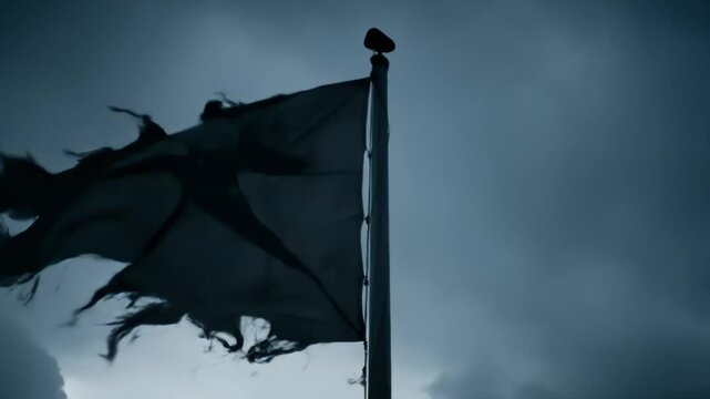 Tattered Flag Waving in Strong Winds Against Dark Sky
