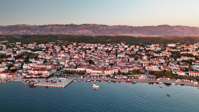Aerial drone view of Novalja on Pag Island at sunset with Velebit mountain in the background, showcasing Croatia&rsquo;s scenic Adriatic coastline and island charm.