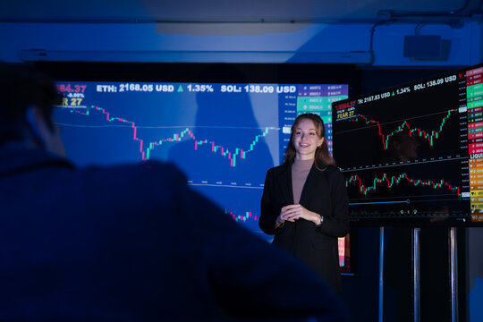 Confident businesswoman leading a financial presentation, explaining stock market and cryptocurrency trends.
