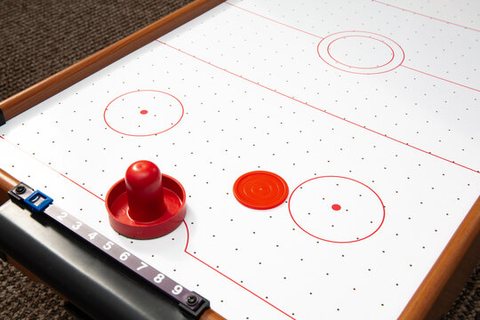 Subject shot of air hockey game table close-up. The portable table hockey includes plastic hockey paddles, a mini puck and score keepers. Hobby game background. Backdrop with copy space. High quality.