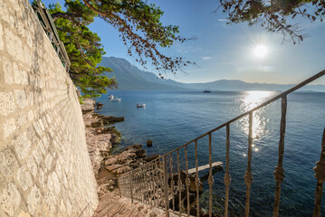 Treppe hinunter zu Felsen am Wasser unterhalb der Stadtmauer von Korcula mit Blick auf Kanal und...