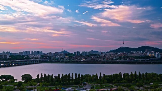 Expansive aerial panorama of Banpo Bridge crossing Han River with Namsan Tower and Seoul city skyline set against dramatic multicolored sky