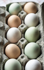 Close up high angle view of cardboard carton of colorful eggs.