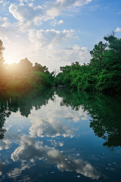 Still River with blue and white puffy cloud reflection and sunlight