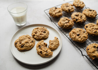 Freshly baked chocolate chip cookies with milk on white background.