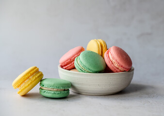 Bowl of assorted colorful macarons on white background.