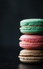 Close up of assorted macaron cookies on black background.