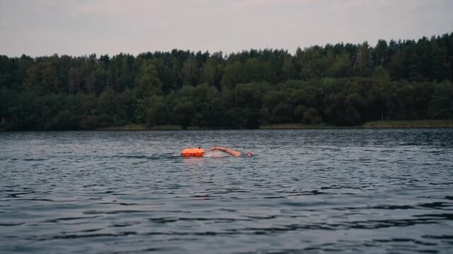 Swimmers in a lake in open water with with a safety buoy