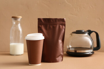 Brown bag with coffee pot, paper cup and bottle of milk on color background