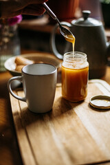 Spoon with honey over jar and cup