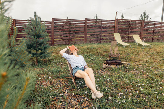 woman relaxes in chair outdoors, book. lounge chairs, fire pit