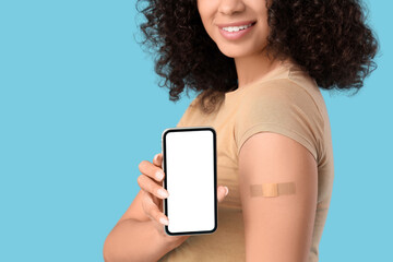Young happy African-American woman with applied medical patch on blue background, closeup