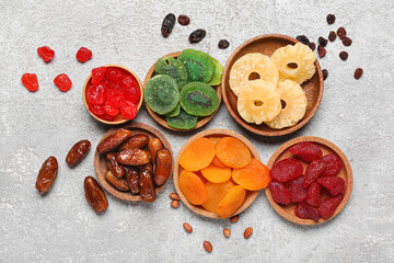 Bowls with different candied fruits and peanuts on grey background
