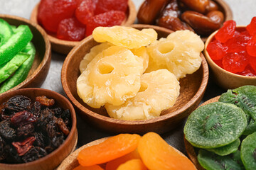 Bowls with different candied fruits on grey background, closeup