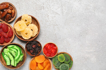 Bowls with different candied fruits on grey background