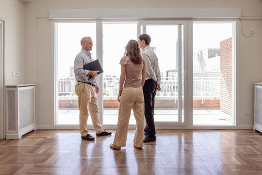 Real estate agent in front of balcony while visit of young couple to apartment for rent - Powered by Adobe