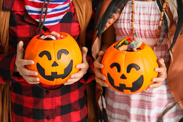 Little children dressed for Halloween with candies in kitchen, closeup