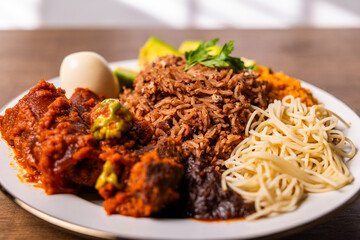 Waakye, Cooked Rice And Beans Served With Tomato Stew, Egg, Gari, Spaghetti, Avocado and Shito, Spicy Pepper Sauce. Africa Ghana Traditional Dish