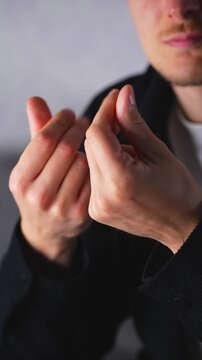 A businessman makes a money gesture with his hands.
The man mimes holding cash.
Money and finance.
Business symbols and signs.
Money gesture with his hands.