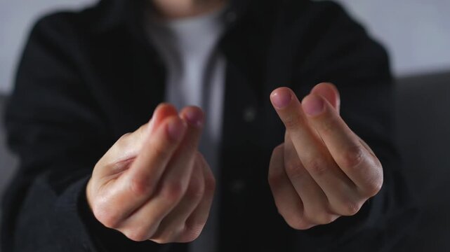 A hand gesture indicating money and cash.
A man rubs his fingers to mimic money.
A man gestures with his fingers to indicate the absence of money.