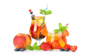 Glasses of cold tea with peach slices, bilberries, strawberries and mint leaves on white background