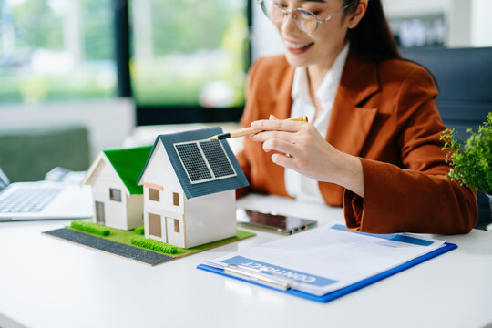 businesswoman presenting calculator with building models. Ideal for real estate finance, property investment, mortgage, and business planning concepts.