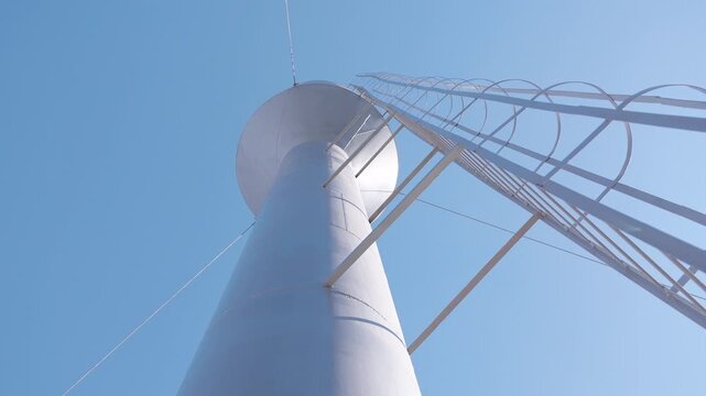 Water tower viewed from below, showcasing structural details and blue sky, with gradual upward camera movement emphasizing height and engineering design elements