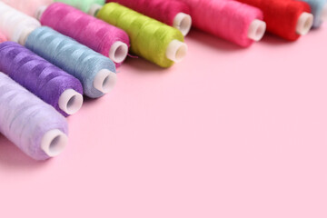Colorful thread spools on pink background