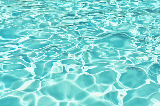 Full frame of sunlight reflecting on rippled turquoise blue surface of swimming pool water
