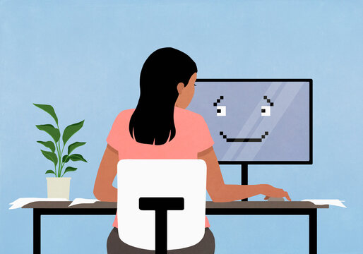 Woman working at computer with smiley face on screen
