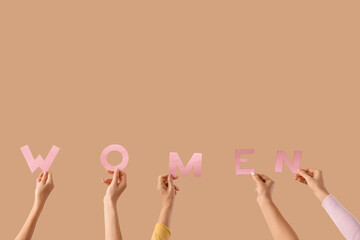 Many female hands with word WOMEN on beige background. Feminism concept