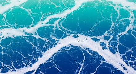 Swirling patterns of white sea foam on the surface of the deep blue and turquoise ocean