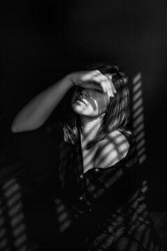 Woman Covering Face with Hand sitting in Window Light