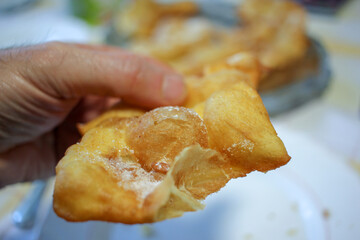 a man holding a piece of fried pastry