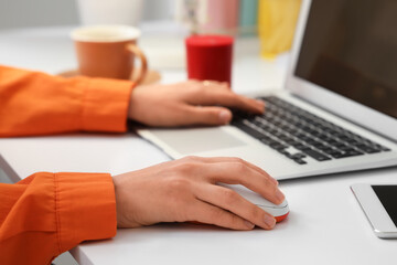 Hands of woman using computer mouse and laptop at table in office