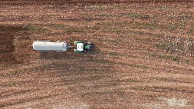 Tractor with bowser sprays liquid manure over agricultural farm field