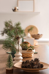 Fototapeta premium Coniferous cones with pine tree branches on table in kitchen