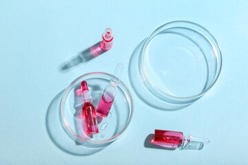 Glass ampoules with Petri dishes on light blue background