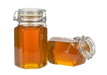 Isolated Glass Jars of Honey with Lid in Upright and Sideways Positions on a Flat Surface