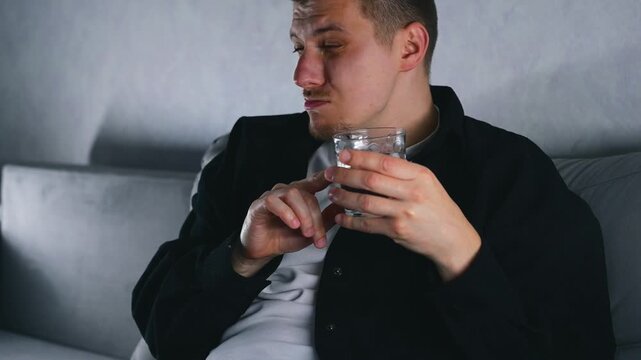 A very drunk man on a sofa with an alcoholic cocktail is talking about something.
Facial expressions of a drunk man.
Alcohol intoxication and regular alcohol consumption