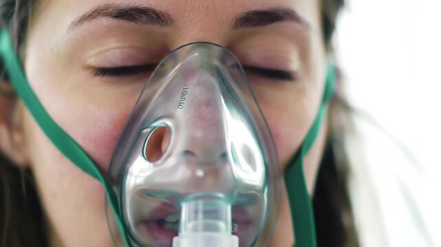 Woman wearing a transparent oxygen mask with green straps