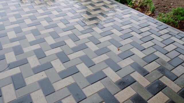 Textured paving stones create a visually appealing pattern on a wet surface, showcasing the intricate design and reflective qualities of the materials in a continuous scene progression
