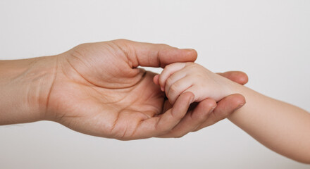Fototapeta premium Parent Holding Baby’s Hand on White Background