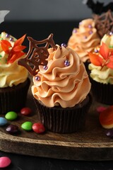 Delicious cupcakes with sprinkles, chocolate web and colorful candies on dark table against grey background, closeup. Halloween celebration