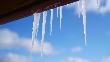 Icicles hang from the roof against a blue sky background