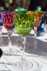 Close-up shot of several colorful glass wine glasses displayed at a street market stall during an antique fair in Nice, France.