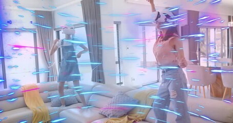 Two women donning VR headsets in room, activating swirling blue pink particles for tech demo