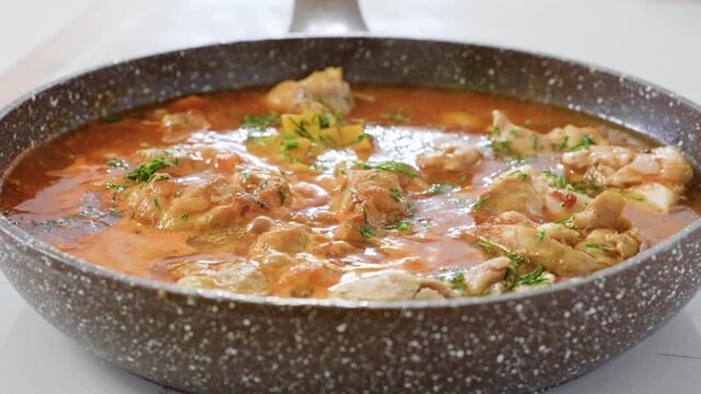 Chicken in tomato sauce with herbs is cooked in a frying pan, chakhokhbili